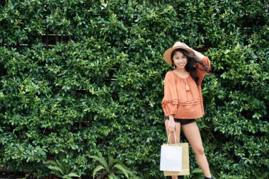 Hedge ayakta ve kameraya gülümseyen güzel gülümseyen genç kadın