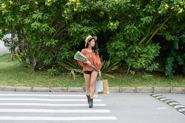 年轻时尚的妇女与花在纸袋横穿路 — 图库照片