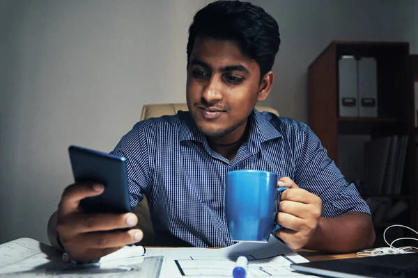 Sonriente Joven Ingeniero Bebiendo Café Comprobando Teléfono Inteligente Mesa — Foto de Stock