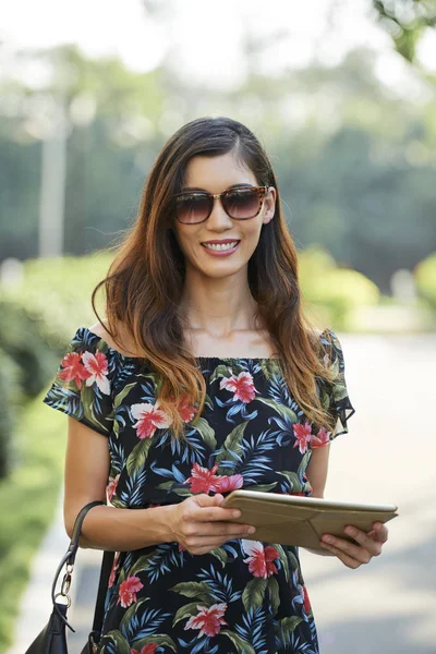 可爱的亚洲女人与可爱的笑容拿着现代平板电脑 看着相机 而站在模糊的背景街道在阳光明媚的日子 — 图库照片