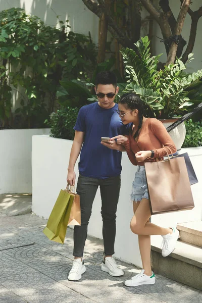 Junges Vietnamesisches Paar Mit Vielen Einkaufstüten Überprüft Mobile Anwendung Auf — Stockfoto