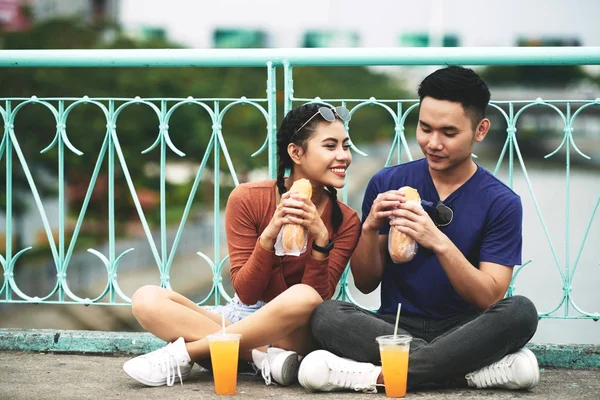 陽気な若いアジアのカップルが屋外に座っていると 屋台の食べ物を楽しんで — ストック写真