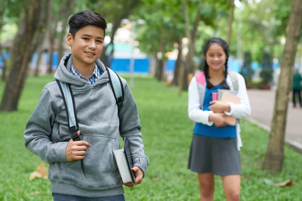 站在校园里的有书的十几岁的男孩 他的同学在背景 — 图库照片