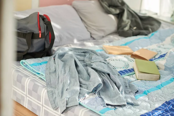 Shirt, books and bag on bed of university student in dorm