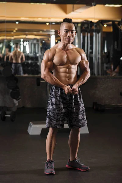 微笑的英俊的越南健美运动员做胸部姿势在镜子前 — 图库照片