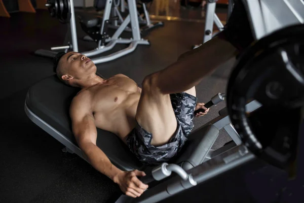 英俊的年轻越南男子在腿压机锻炼重在健身房 — 图库照片