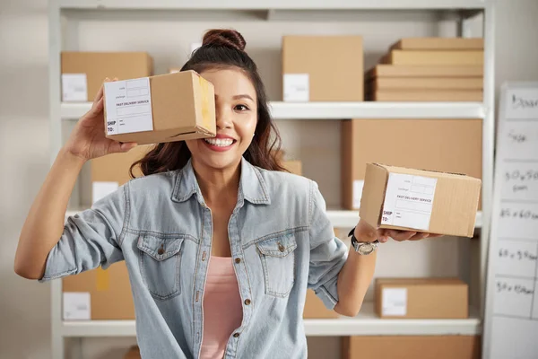 快乐的亚洲女人拿着小包装的包裹给顾客 她在仓库里 — 图库照片
