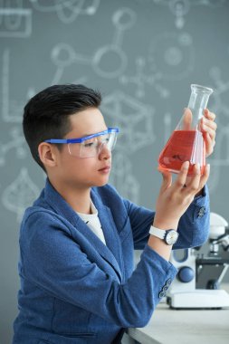 Meraklı Asyalı liseli okul laboratuvarında büyük Flask sıvı inceleniyor 