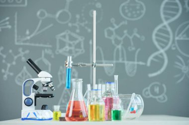 Mikroskop, flsorlar ve test tüpleri ile okul laboratuarında tablo