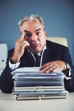 Onun önünde belgelerin yığınına meyilli yorgun olgun işadamı portre