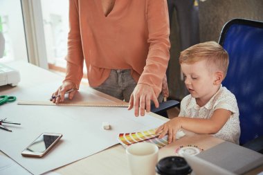 Annesi proje ile meşgul zaman küçük çocuk renk paleti ile oynuyor