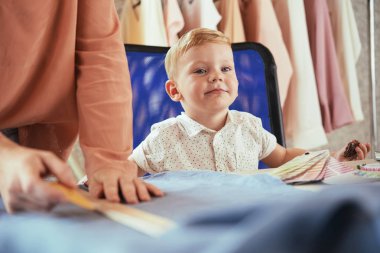 Annesinin dikiş atölyesinde küçük çocuk