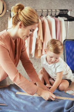 Genç kadın onu stüdyosunda kumaş ile nasıl çalıştığını oğlunu gösteren