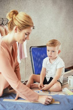Anne giyim öğe üzerinde iş ile bitmiş zaman bekleyen Pensive küçük çocuk
