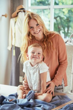 Dikiş atölyesinde neşeli anne ve küçük oğul portresi