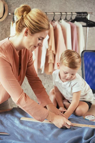 Genç kadın onu stüdyosunda kumaş ile nasıl çalıştığını oğlunu gösteren