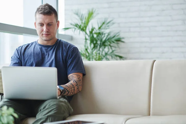 Νέος Άνθρωπος Κάθεται Άνετο Καναπέ Και Δουλεύοντας Για Laptop Στο — Φωτογραφία Αρχείου