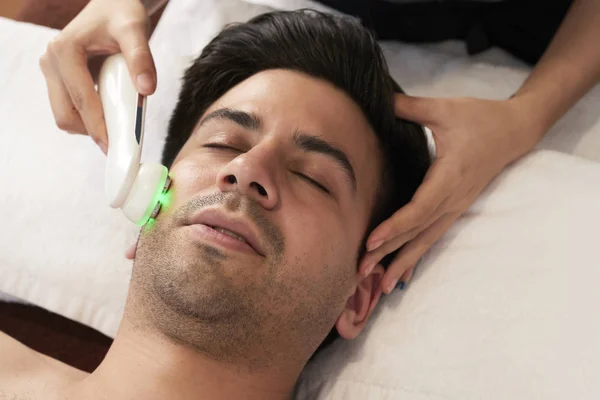 Bonito Homem Deitado Relaxante Com Olhos Fechados Enquanto Cosmetologista Massageando — Fotografia de Stock