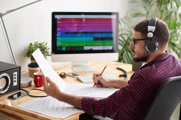 Joven Concentrado Auriculares Mirando Papeles Con Partituras Componiendo Una Canción — Foto de Stock