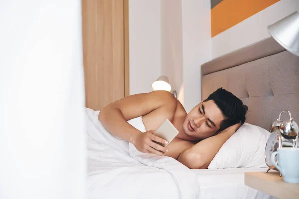 Guapo Joven Vietnamita Hombre Acostado Cama Con Teléfono Inteligente —  Fotos de Stock