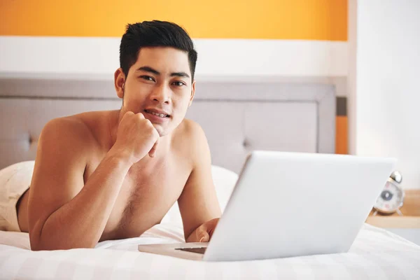 Knappe Positieve Jonge Man Rust Bed Met Laptop — Stockfoto