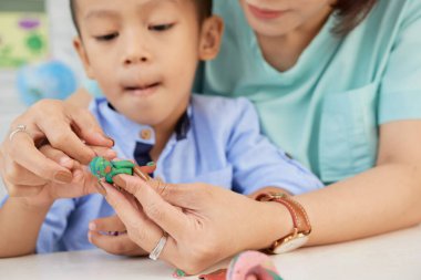 Kırpma tanınmaz öğretmen sanat sınıfında plastik heykelcik ile küçük Asyalı çocuk yardım