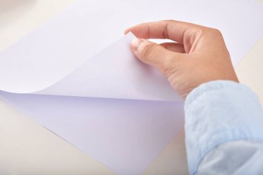 Ofiste çalışırken boş beyaz kağıt yapraklar arasında çeviren isimsiz bir kişinin kırpma eli yukarıdan