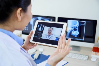Kıdemli erkek doktor x-ray görüntü tartışırken veya ofiste tablet pc'de onun kadın asistanı online bir talimat veren