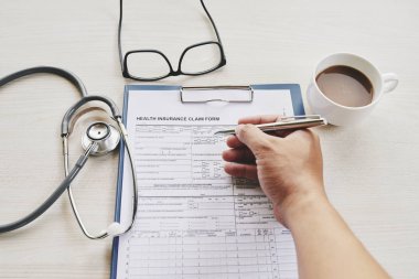 Kahve içen ve sağlık sigortası formu dolduran hasta