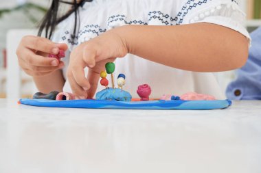 Sanat sınıfında plastikle oynayan tanınmayan kızın kırpma elleri