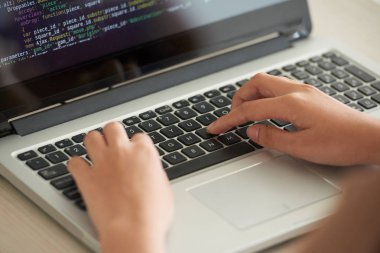 Programcı ofiste dizüstü bilgisayar üzerinde çalışıyor ve kod yazma