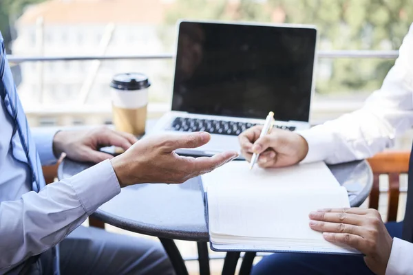 Close Van Twee Zakenlieden Zittend Aan Tafel Voor Kladblok Schrijven — Stockfoto