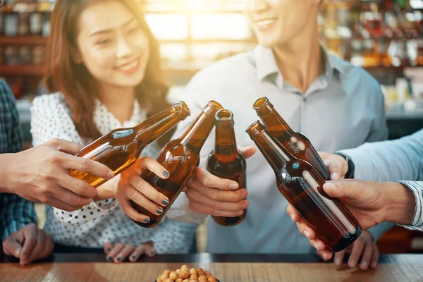 Crop Cheerful Friends Clinking Beer Bottles Bright Sunlight Standing Counter — Stock Photo, Image