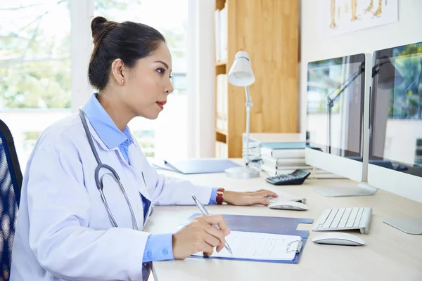 Jovem Médica Asiática Sentada Mesa Fazendo Anotações Documento Concentrada Seu — Fotografia de Stock