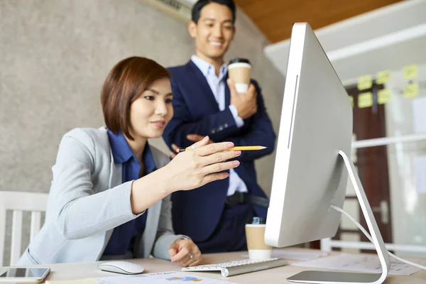 コンピュータ画面上で彼女の同僚の情報を示す笑顔かわいいアジアのビジネス女性 — ストック写真