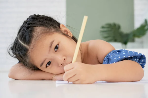 愛らしい若いアジアの女の子は鉛筆を持って 芸術のクラスでテーブルの上に横たわって — ストック写真