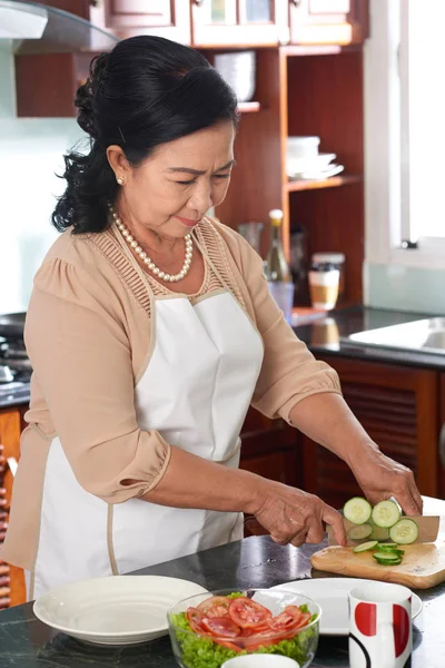 Senior Vietnamese Vrouw Snijden Komkommer Voor Salade — Stockfoto
