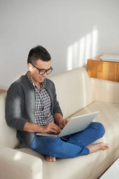 Lycklig Ung Asiatisk Man Sitter Soffan Och Arbetar Laptop — Stockfoto