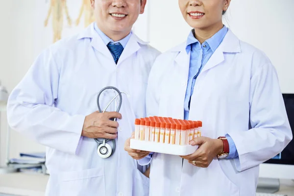 Dos Científicos Sonrientes Con Bata Laboratorio Sosteniendo Tubos Ensayo Mientras —  Fotos de Stock