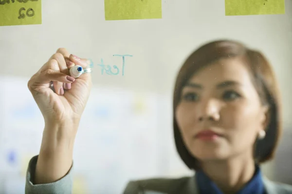 Ernsthafte Junge Vietnamesische Geschäftsfrau Schreibt Ideen Glaswand Büro — Stockfoto