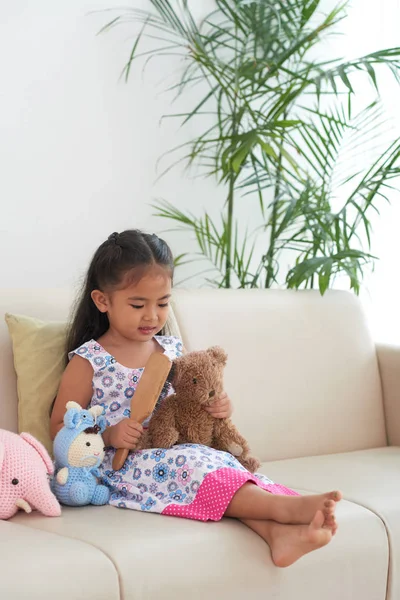 可爱的小女孩坐在家里的坐的和梳理泰迪熊 — 图库照片