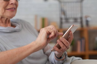 Akıllı telefonda uygulama kullanan kıdemli kadının elleri