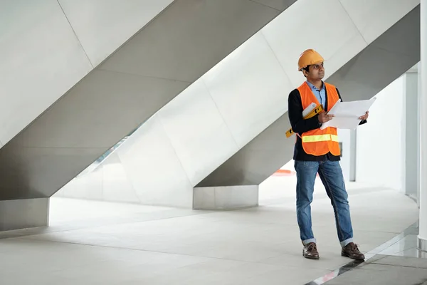 Construction worker in hardhat and vest examining new building