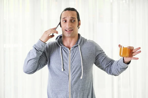 Zeer Nerveuze Jonge Man Met Glas Sinaasappelsap Praten Telefoon — Stockfoto