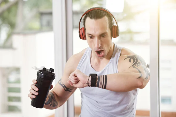 Zaskoczony Emocjonalnym Sportowcem Słuchawkach Patrząc Fitness Tracker Nadgarstku — Zdjęcie stockowe
