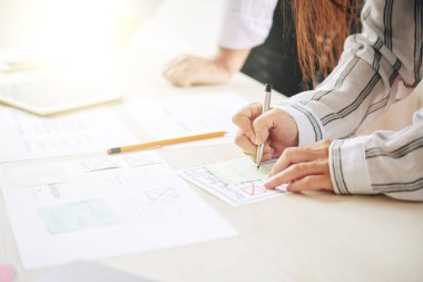 Masa başına şemalar ve verilerle çalışırken not kağıdına not veya anımsatıcı yapan meşgul analist