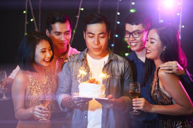 Yakışıklı genç adam partisinde doğum günü pastası üzerinde mum üfleme