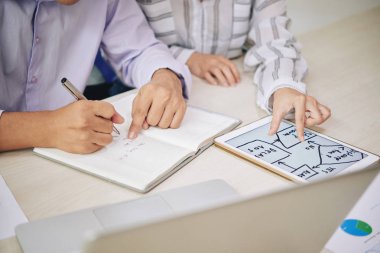 İki iş arkadaşı masa başında otururken, verilerle dijital düzeni analiz eder ve çalışma notları