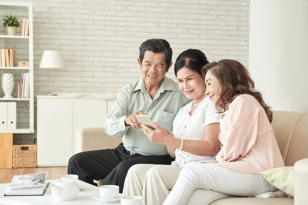 Gente Vietnamita Edad Alegre Descansando Casa Mirando Fotos Teléfono Inteligente —  Fotos de Stock