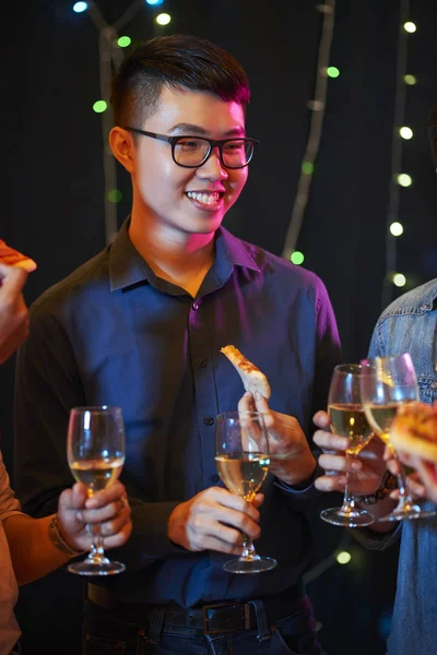 Handsome Asian man in glasses enjoying partying with friends on Friday night